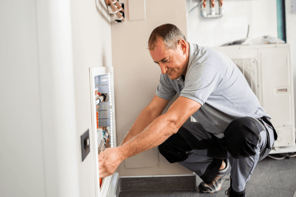 a man fixing an electrical outlet in a home.