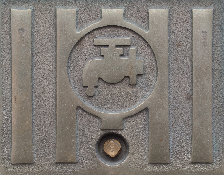 Metal plate showing tap symbol indicating access to main water supply